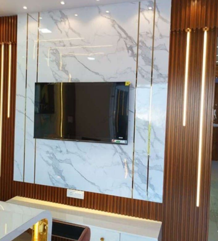 TV unit with white marble wall panelling, gold inlay strips and wooden rafters in Bikaner